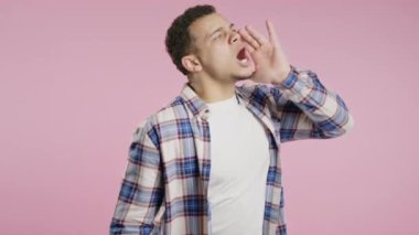 Dikkat, Afro-Amerikan kıvırcık adamın portresi bağırıyor, el ele tutuşuyor, pembe arka planda izole edilmiş ve ilanınız için fotokopi çekiliyor. Yüksek kalite 4k