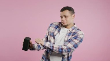 Erkek dansı, pembe stüdyo arka planında eğlenmek. Adam müziğin ritmine göre hareket ediyor. Genç adam kablosuz taşınabilir hoparlörden müzik dinliyor. Modern ses sistemi. Yüksek kalite 4k