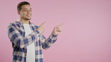 Gülümseyen genç adam reklamınız için boş bir yer arıyor. Sağ tarafı gösteren adam öneriliyor, boşluğu kopyalayın. Erkek model pembe arka planda izole edilmiş bir şey sunuyor. Yüksek kalite 4K görüntü.