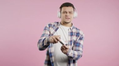 Pembe stüdyo arka planında joystick izole edilmiş video oyunu oynayan yakışıklı Afro-Amerikalı bir adam. Modern teknolojiyi kullanarak.