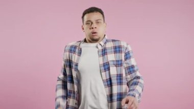 Şok olmuş korkmuş bir adam bir şeyden korkuyor ve pembe arka planda korku dolu büyük gözlerle kameraya bakıyor. Fobi, sorun, panik konsepti. Yüksek kalite 4k