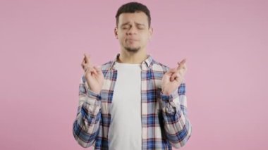 Genç adam pembe arka planda dua ediyor. Adam birine arzularını tatmin etmesi için yalvarıyor, yardım ediyor, sınavda şans için dua ediyor. Yüksek kalite 4k görüntü