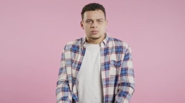 Sinirli bir adam kamerayı gösterip nasıl bir jest yaptığını gösteriyor. Deli misin diye soruyorum. Kavgacı adam pembe arka planda izole edilmiş. Öfkeli ifade, birini suçlamak..