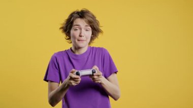 Televizyonda video oyunu oynayan genç ve güzel bir kadın. Oyun kolu sarı stüdyo arka planında izole edilmiş. Modern teknolojiyi kullanarak. E-spor, hobi, akış