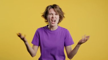 Sinirli bir kadın kamerayı işaret ediyor ve nasıl bir jest yaptığını gösteriyor. Deli misin diye soruyorum. Münakaşa eden kadın sarı arka planda izole edilmiş. Öfkeli ifade, birini suçlamak..