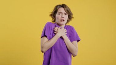 Bir şeyden korkan kadın, sarı arka planda şoka girmiş. Başını tutuyor, çığlık atıyor. Yüksek kalite 4k