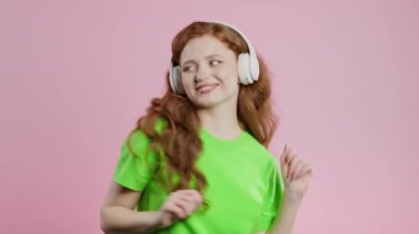 Mutlu kadın kafayı bulur, müzik dinler, pembe stüdyo arka planında kulaklıklarla dans etmekten zevk alır. Radyo, kablosuz modern ses teknolojisi, çevrimiçi çalar. Yüksek kalite 4k