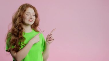 Gülümseyen genç bayan reklamınız için boş bir yer arıyor. Önerilen kadın sağ tarafı işaret ediyor, boşluğu kopyalayın. Kadın, pembe arka planda izole edilmiş bir şey sunuyor. Yüksek kalite 4k