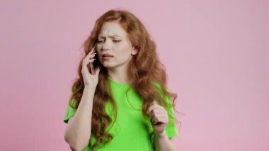 Sinirli genç bir kadın cep telefonuyla konuşurken kavga ediyor. Stresli kızgın bir kadın. Pembe stüdyo geçmişi. Çatışma, anlaşmazlık, olumsuz. Yüksek kalite 4k görüntü
