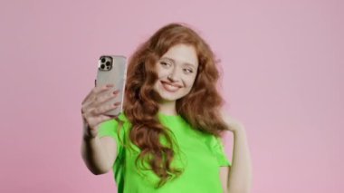 Gülümseyen blogcu kadın çevrimiçi video blogu yapıyor, vlog, pembe arka planda akıllı telefonu olan. Konferans kayıtları sırasında kameraya konuşan nüfuzlu biri. Yüksek kalite 4k görüntü