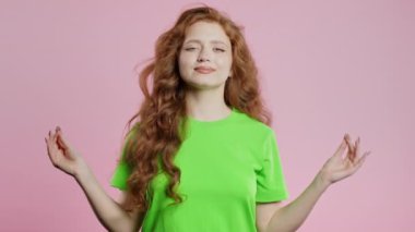 Sakin bir kadın dinleniyor, meditasyon yapıyor, stresi reddediyor. Kızıl kadın derin nefes alır, sakinleşir, pembe stüdyo arka planı. Yoga, ahlaki denge, zen konsepti. Yüksek kalite 4k görüntü