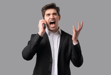 Öfkeli yetişkin iş adamı tartışıyor, cep telefonundan bağırıyor. Stres ve çatışma içindeki patron menajeri. Gri stüdyo geçmişi. Tartışma, olumsuz, intikam. Yüksek kalite