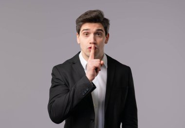 Yakışıklı Avrupalı esmer iş adamı. Şşş, sır, sessizlik, komplo, dedikodu konsepti. Gülümseyen patron, parmaklarını dudağında tutuyor, beyaz stüdyo geçmişi var. Yüksek kalite