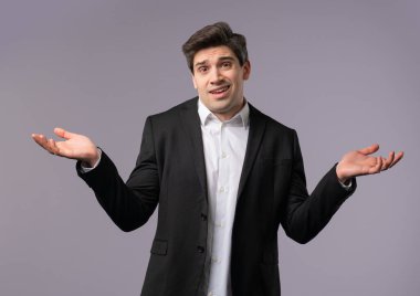 30 'lu yaşlarda, resmi giyinmiş, omuzları yukarıda kafası karışmış bir iş adamı. Yardımcı olamıyor. Bilmiyorum. Zor bir soru, suçlu tepkisi, gri arka planda kafası karışık bir adam. Yüksek kalite