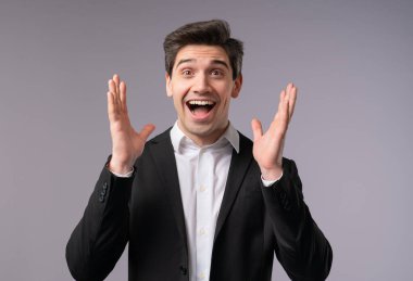 Olgun, yakışıklı, şok olmuş iş adamı seviniyor, çığlık atıyor. Etkilenmiş patron ofis şefi, dikkat. Kârlı büyük haber teklifi kavramı. Gri arka planda heyecanlı bir CEO. Yüksek kalite