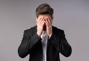 Resmi ofis kıyafetli hayal kırıklığına uğramış işadamı facepalm yapıyor. Pişmanlık, başarısızlık, tatminsizlik, zaman kaybı, ofiste sorunlar, gri stüdyo geçmişi. Yüksek kalite