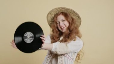 Güzel bir kadın bej plakla dans ediyor. Hobi, müzik aşığı, koleksiyon, nostalji yaşam tarzı. Yüksek kalite 4k