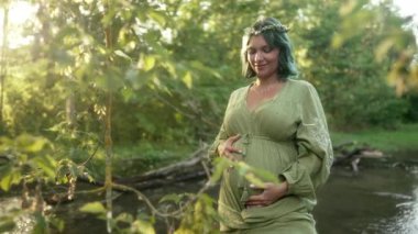 Müstakbel anne bebek bekliyor. Sağlık hamileliği, mutlu annelik. Orman nehrinde karnı şişmiş hamile bir kadın, doğal bir geçmişi var. Yüksek kalite 4k görüntü