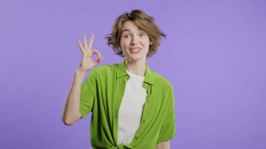 Güzel bir kadın el işareti yaptırır, tamam mı? Mutlu kız, doğru seçim, harika anlaşma, menekşe arkaplan. Pozitif kadın model kameraya gülümser, onay, güven konsepti. kalite 4k