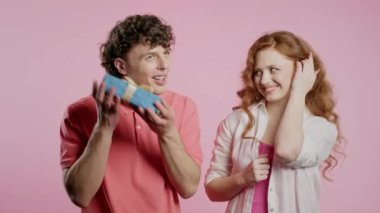Pembe stüdyo geçmişi olan genç bir Amerikalı çift. Beyaz kadın kocasına ya da erkek arkadaşına selam verir. Doğum günü, kutlama, sürpriz, yıldönümü konsepti. Yüksek kalite 4k görüntü