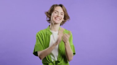 Mor arka planda alkışlayan mutlu stil sahibi kadın. Gülümseyen bayan el çırpıyor, tebrik ediyor. Destek, tezahürat, minnettarlık, bravo konsepti. Yüksek kalite 4k görüntü