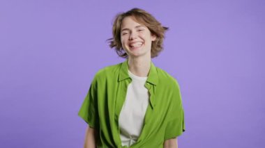 Çekici kadın, doğal güzellik. Menekşeli genç kız, güzel gözler, kısa saç stili. Amerikan görüntüsü kameraya bakıyor. Mor arka planda yeşil gömlek. Yüksek kalite 4k görüntü