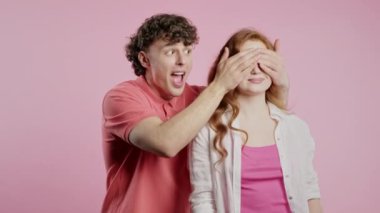 Yakışıklı Adam Sürprizden Önce Sevgili Kız Arkadaşının Gözlerini Kapar. Pembe stüdyo geçmişi olan bir çift. Aşk, tatil, mutluluk konsepti. Yüksek kalite 4k