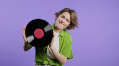 Violet 'te plak CD' siyle dans eden güzel bir kadın. Hobi, müzik aşığı, koleksiyon, nostalji yaşam tarzı. Yüksek kalite 4k görüntü