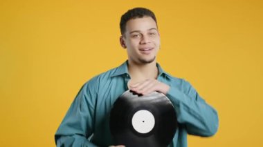 Zarif, yakışıklı, Afro-Amerikalı bir adam, sarıda plak plak CD 'siyle dans ediyor. Hobi, müzik aşığı, koleksiyon, nostalji yaşam tarzı. Yüksek kalite 4k görüntü