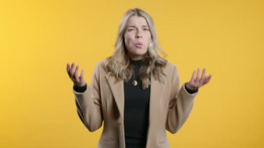 Sinirli iş kadını kamerayı gösterip nasıl bir jest yaptığını gösteriyor. Deli misin diye soruyorum. Kavga eden kadın sarı arka planda izole edilmiş. Öfkeli ifade, birini suçlamak..