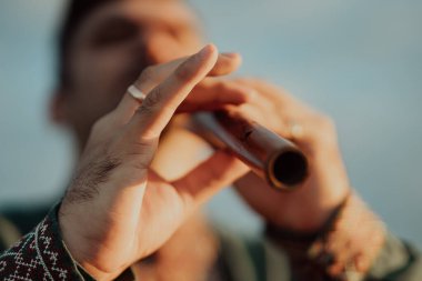 Tahta flüt çalan genç adam - Ukraynalı sopilka. Halk müziği konsepti. Müzik aleti. Geleneksel nakışlı gömlekli müzisyen - Vyshyvanka. 