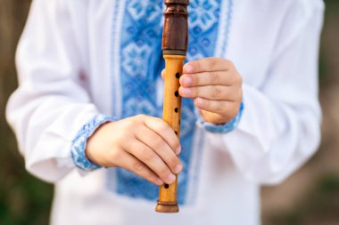 Ukrayna usulü ahşap flüt çalan küçük çocuğun elleri. Halk müziği konsepti. Müzik aleti. Geleneksel nakışlı gömlekli müzisyen Vyshyvanka. Yüksek kalite fotoğraf