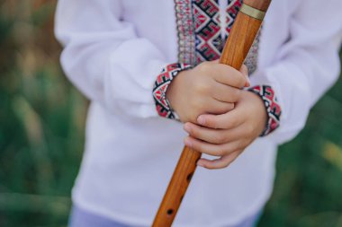 Ukrayna usulü ahşap flüt çalan küçük çocuğun elleri. Halk müziği konsepti. Müzik aleti. Geleneksel nakışlı gömlekli müzisyen Vyshyvanka. Yüksek kalite fotoğraf