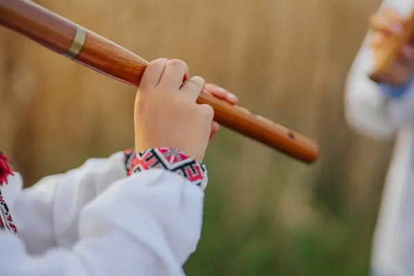 stock image Hands Of Little Boy Kid Playing On Woodwind Wooden Flute - Ukrainian Sopilka. Folk music concept. Musical instrument. Musician in traditional embroidered shirt - Vyshyvanka. High quality photo