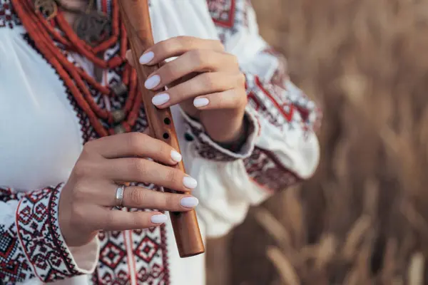 stock image Woman playing woodwind wooden flute - ukrainian sopilka outdoors. Folk music concept. Musical instrument. Lady in traditional embroidered shirt - Vyshyvanka. High quality photo