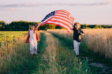 Sevimli küçük çocuklar - Amerikan vatansever çocuklar açık arazi yolunda ulusal bayrak sallayarak koşuyorlar. ABD, 4 Temmuz - Bağımsızlık Günü, Kutlama. Amerikan bayrağı, Gaziler Anıtı, seçim. Yüksek kalite