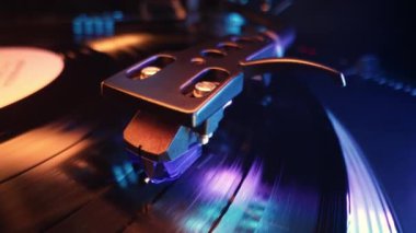 Vinil oynatıcıya renkli ışıkta dönen plak. Yakın çekim görüntüsü. Neon altında canlı bir film. Analog ses ekipmanı konsepti, klasik parti.