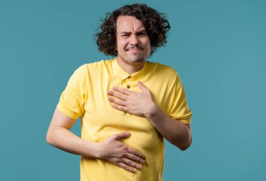 Karın ağrısı yüzünden karnını ellerinle sıkan bir adam. Yetişkin adam mide ağrısı çekiyor. Sağlık hizmetleri, sindirim sistemi, gıda zehirlenmesi veya bağırsak gazı konsepti