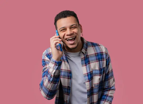 stock image Smiling positive african american guy talking by phone, nice joke, smiling. Young man on pink background. Having smartphone call. High quality 