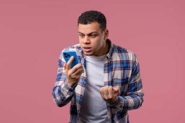 Sinirli bir Afrikalı adam cep telefonuyla konuşurken kavga ediyor. Kızgın adam, stres. Pembe stüdyo geçmişi. Çatışma, anlaşmazlık, olumsuz. Yüksek kalite