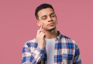 Pembe arka planda gül kuvars taşından tekerlekli genç bir Afrikalı. Yüz bakımı, güzellik ritüelleri, kozmetoloji, yaşlanmayı önleme ve kırışıklık önleme tedavisi. Uzayı kopyala Yüksek kalite