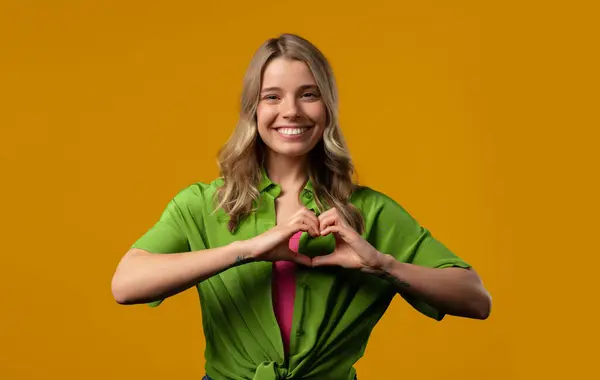 stock image Smiling woman showing sign of shape heart. Positive lady on yellow. Love. Women health, volunteering, charity donation, gratitude symbol, flirting concept. High quality photo