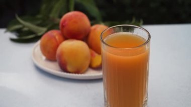 Masada taze sıkılmış meyve suyuyla olgunlaşmış şeftalilerin iştah açıcı görüntüleri. Sağlıklı yiyecekler, vitaminler, meyve ağacından yaz hasadı. Kamera soldan sağa hareket ediyor. Yüksek kalite 4k görüntü 