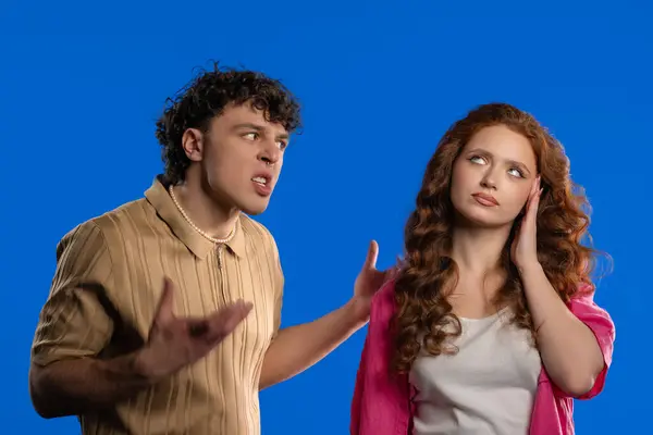 stock image Grumpy man Emotionally Screaming On Wife Or Girlfriend On blue. Bored woman rolling eyes. Concept of conflict, quarrel, problems in couple relationships. High quality