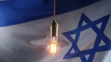 David Star arka planında İsrail bayrağı sallayan klasik Edison Tungsten filament lambası. Yaratıcı fikir, farkındalık, keşif, eureka. Yüksek kalite 4k görüntü