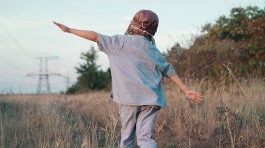 Pilot kasklı mutlu çocuk şehrin dışındaki doğa çayırında uçak gibi koşuyor. Çocukların hayali pilot olmaktır. Git, her yere git, kaygısız, aktif çocukluk yaşam tarzı. Yüksek kalite 