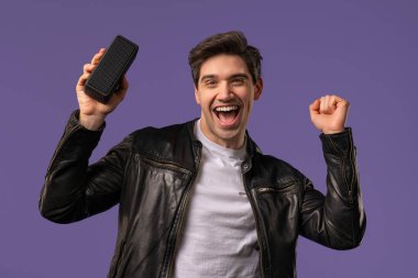 Erkek dansı, Violet stüdyosunun arka planında eğlenmek. Adam müziğin ritmine göre hareket ediyor. Genç adam kablosuz taşınabilir hoparlörden müzik dinliyor. Modern ses sistemi. Yüksek kalite