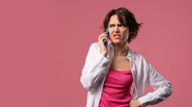 Sinirli genç bir kadın cep telefonuyla konuşurken kavga ediyor. Stresli kızgın bir kadın. Pembe stüdyo geçmişi. Çatışma, anlaşmazlık, olumsuz. Yüksek kalite 