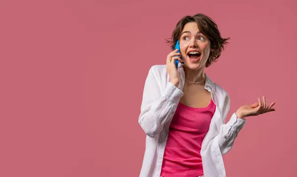 stock image Attractive woman talking by phone, nice joke, smiling. Young lady on pink background. Having smartphone call. . High quality