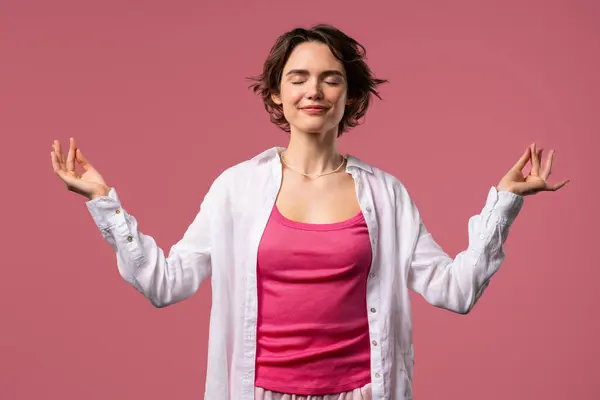 stock image Calm woman relaxing, meditating, refuses stress. Pretty lady breathes deeply, calms down, pink studio background. Yoga, moral balance, zen concept. High quality 